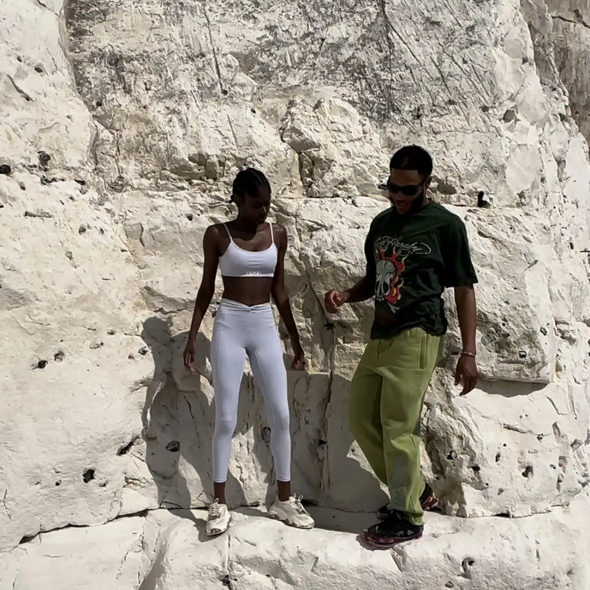 female black model and male assistant posing in front of a rock