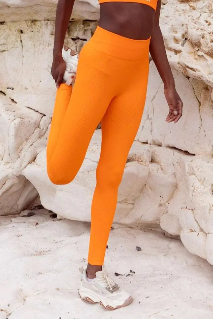 model wearing orange leggings in front of a cliff