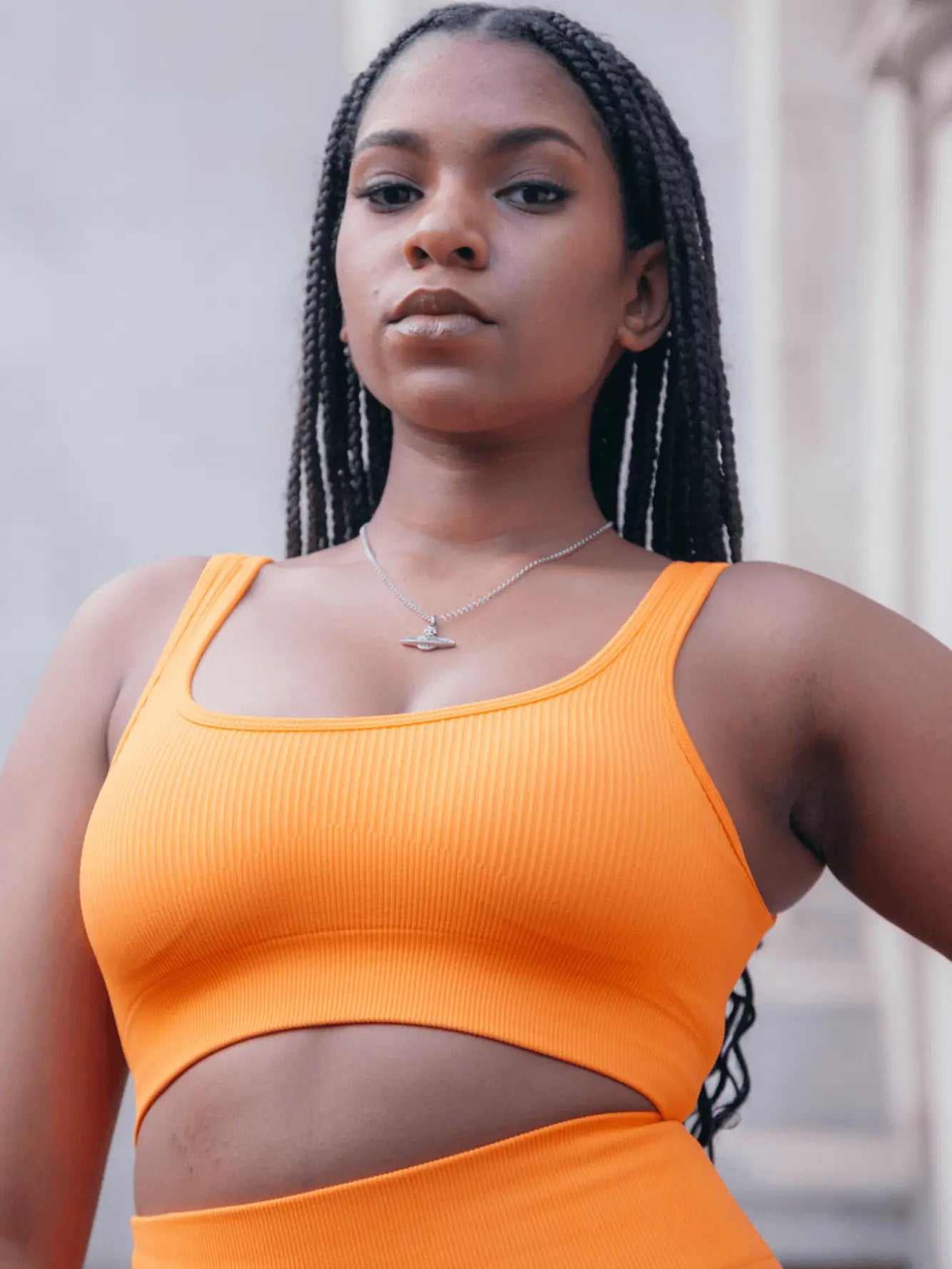 blasian model in a orange sports bra looking fierce