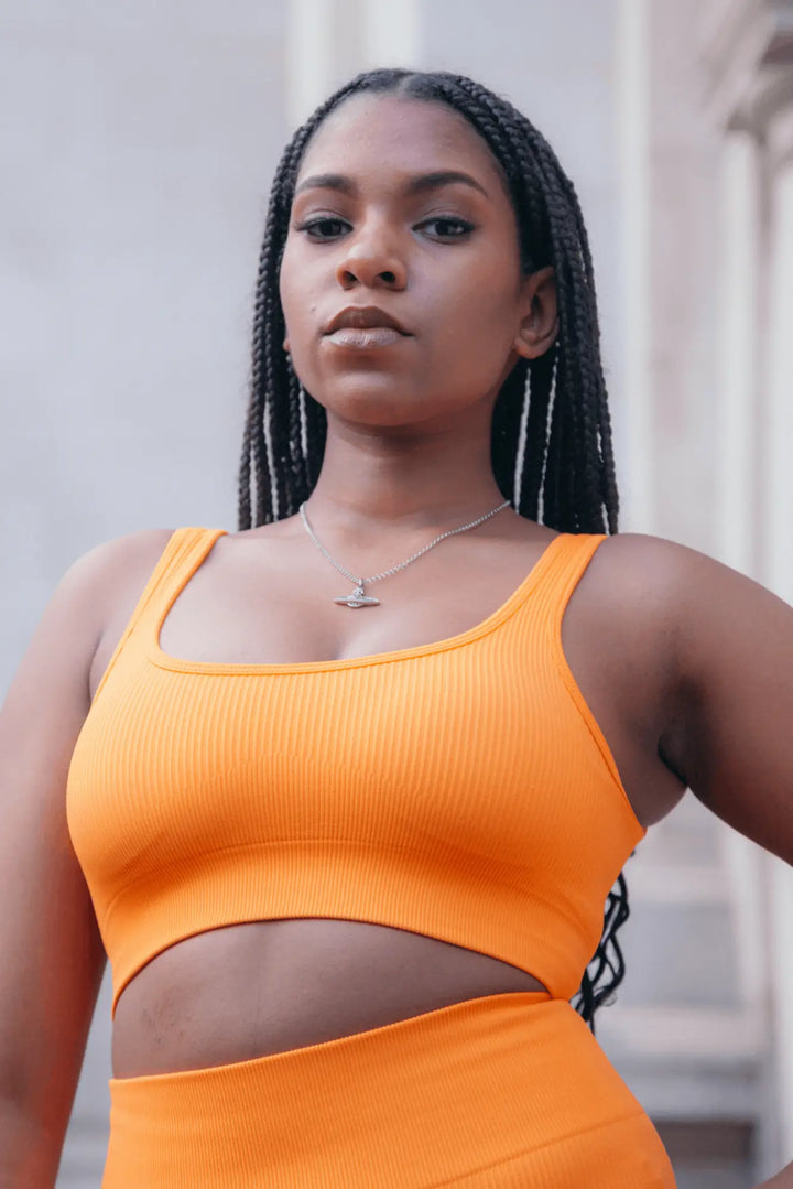 blasian model in a orange sports bra looking fierce