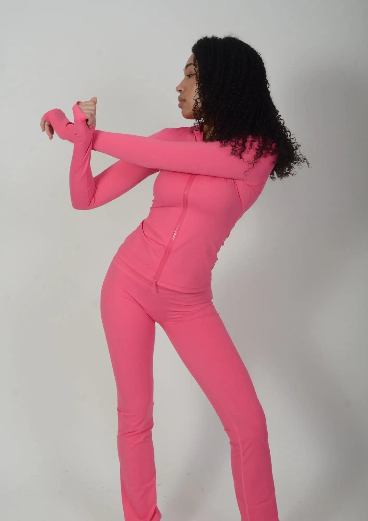 A vibrant pink, form-fitting two-piece athletic suit with long sleeves and zipper details.