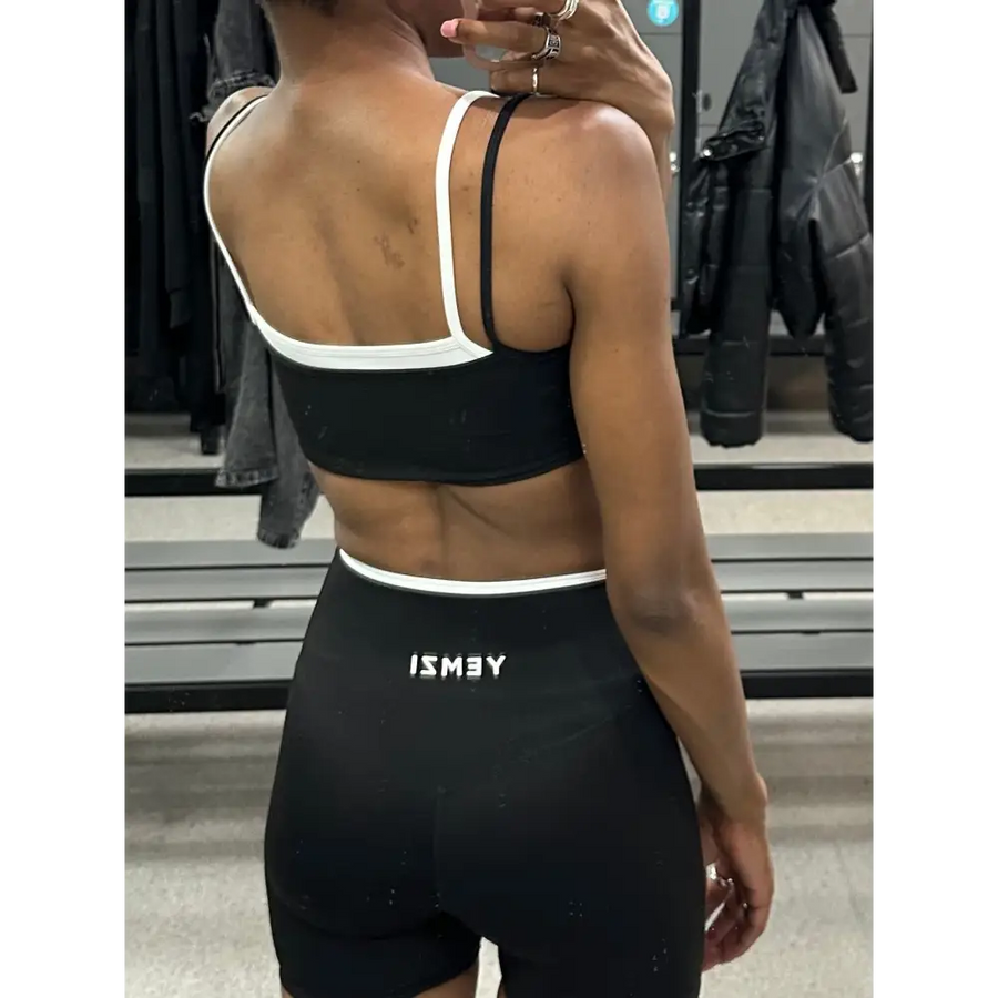 Person wearing a black sports bra and shorts with 'ISMEY' branding in a clothing store.