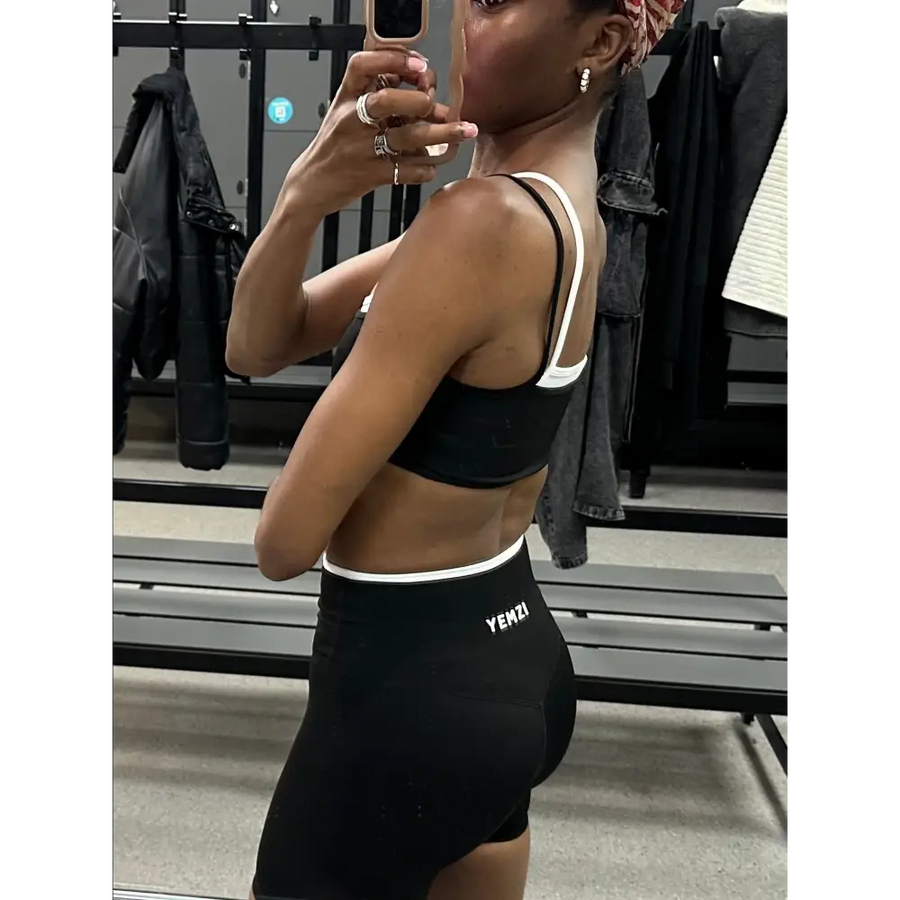 Person wearing a black sports bra and shorts in a gym setting