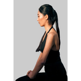 Woman in black outfit sitting on stone steps with a blurred reflection in the mirror.