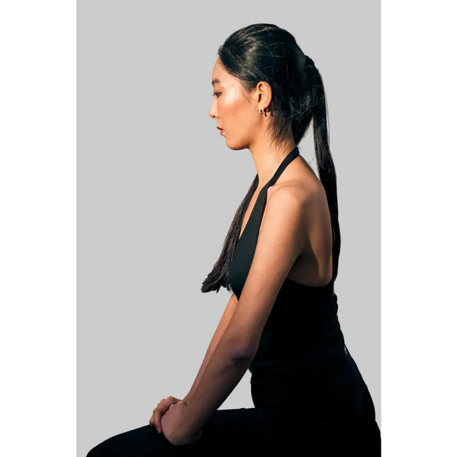 Woman in black outfit sitting on stone steps with a blurred reflection in the mirror.