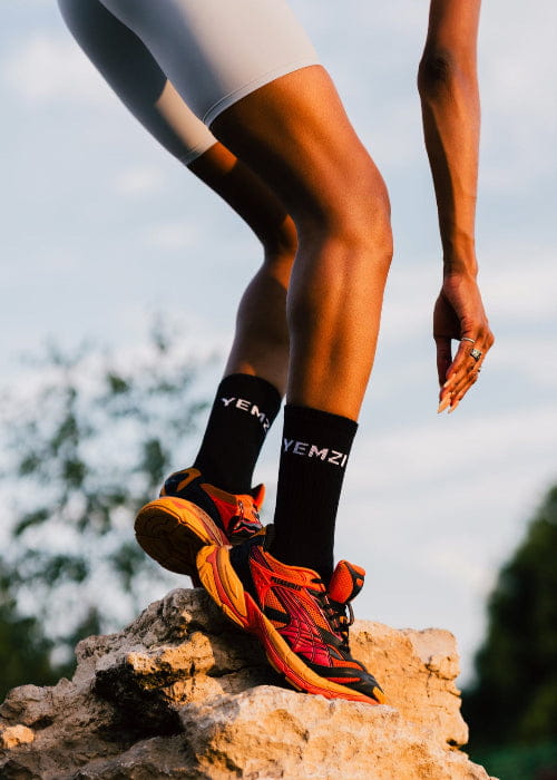 african model wearing puma shoes and yemzi socks on a rock with a blurred natural background