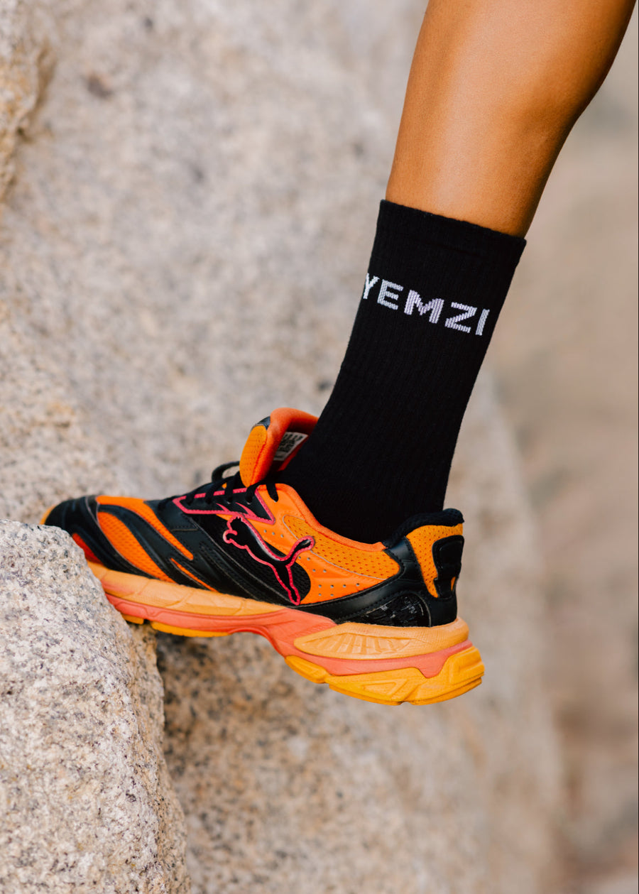 Orange and black puma running shoe with a blurred background