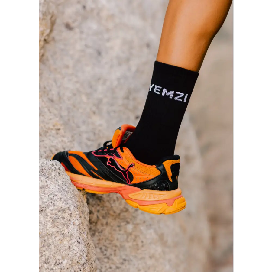 Orange and black puma running shoe with a blurred background