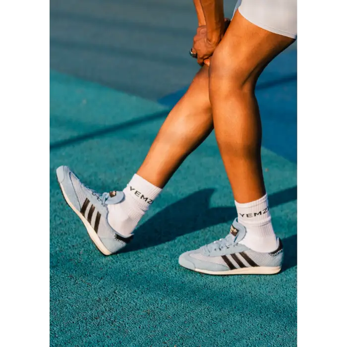 black model wearing light blue grace wales bonner Adidas sneakers with white socks on a tennis court.