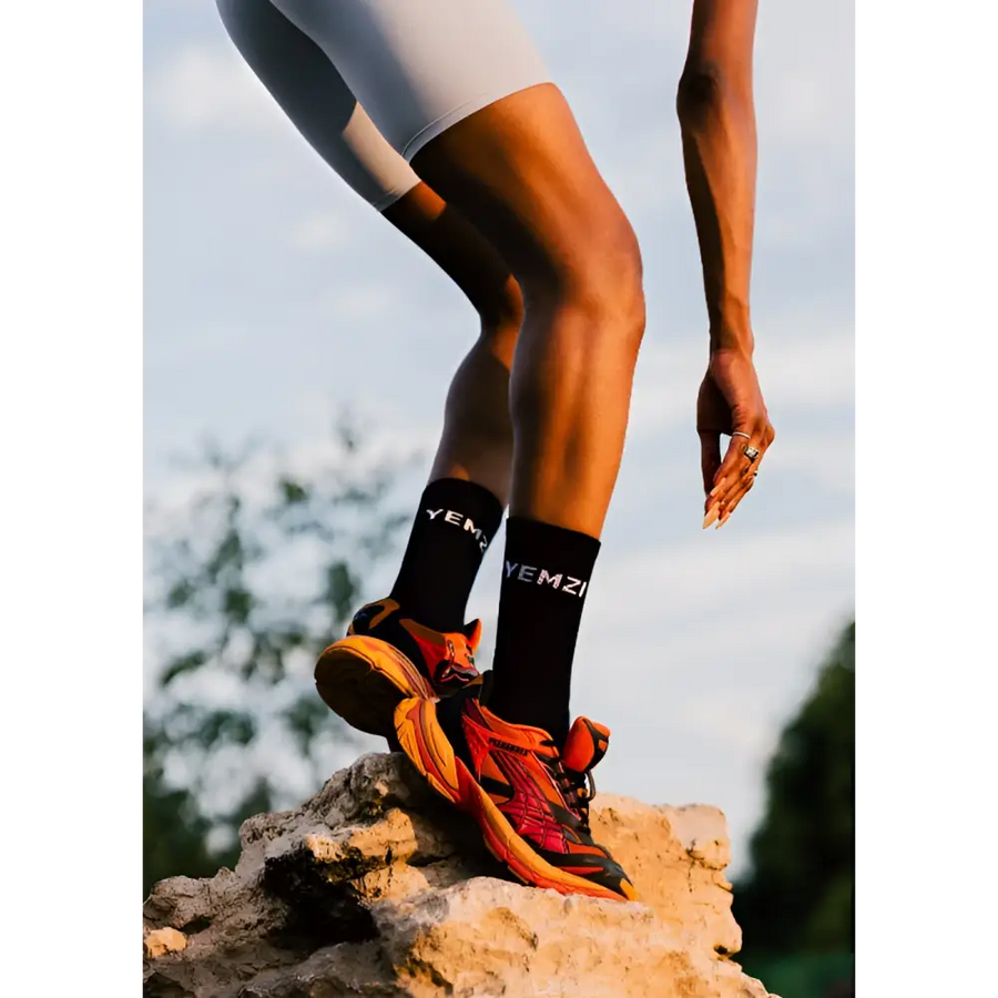 african model wearing puma shoes and yemzi socks on a rock with a blurred natural background