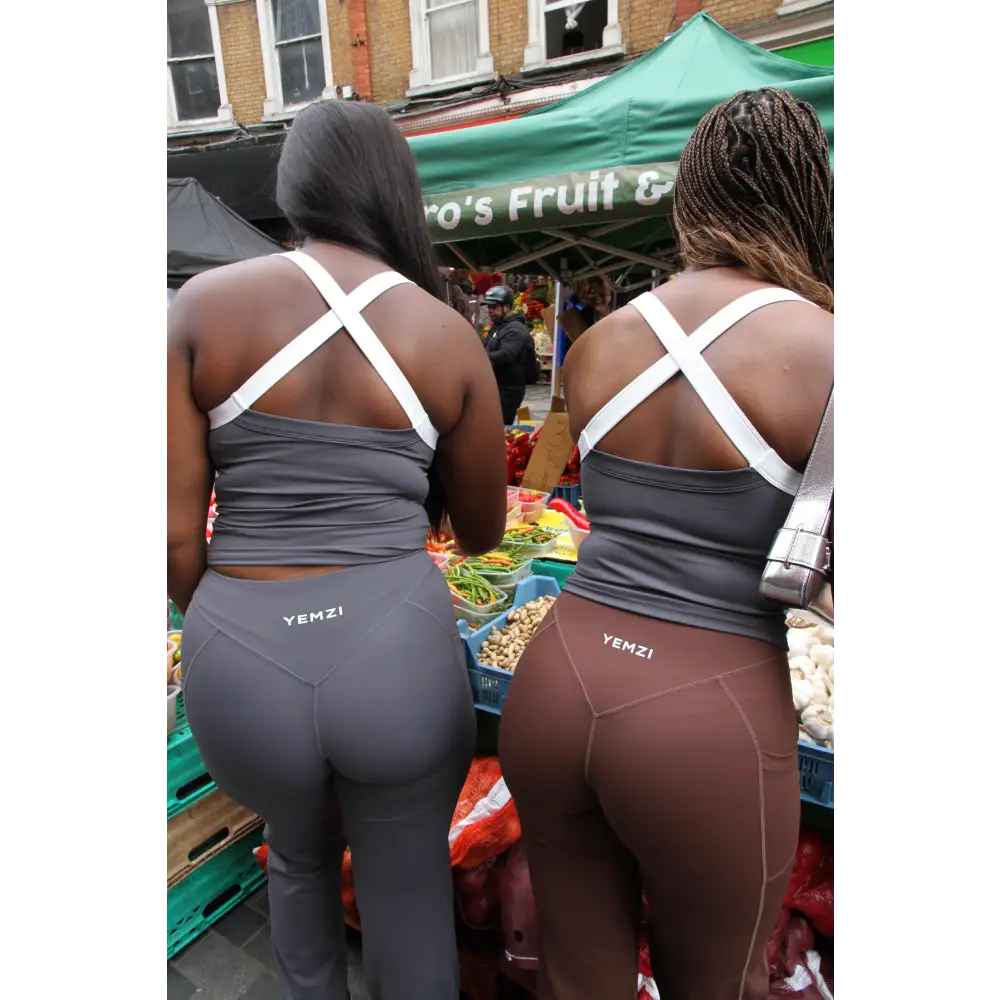 Two women wearing Yemzi top and leggings at an outdoor market.