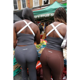 Two women wearing Yemzi top and leggings at an outdoor market.