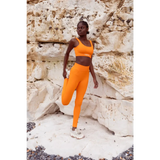 Model wearing Yemzi Orange fanta ribbed two piece leggings bra activewear set in rocky outdoor location - stretch