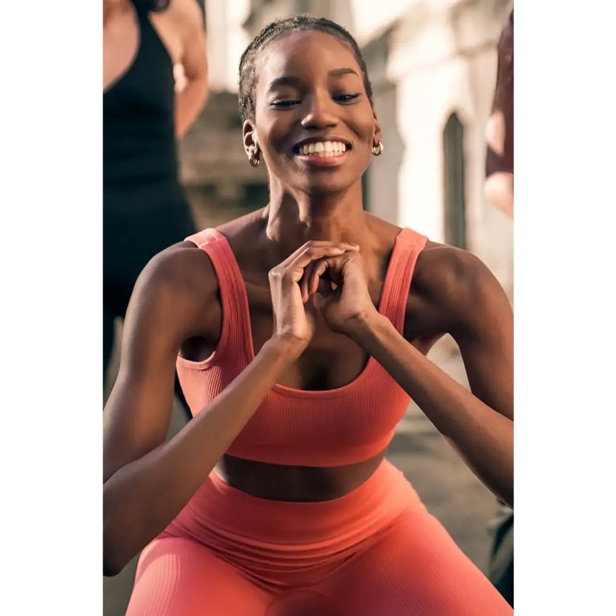Woman in pink athletic wear smiling outdoors
