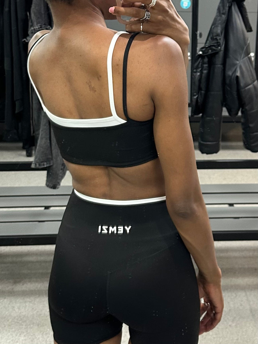 Person wearing a black sports bra and shorts with 'ISMEY' branding in a clothing store.