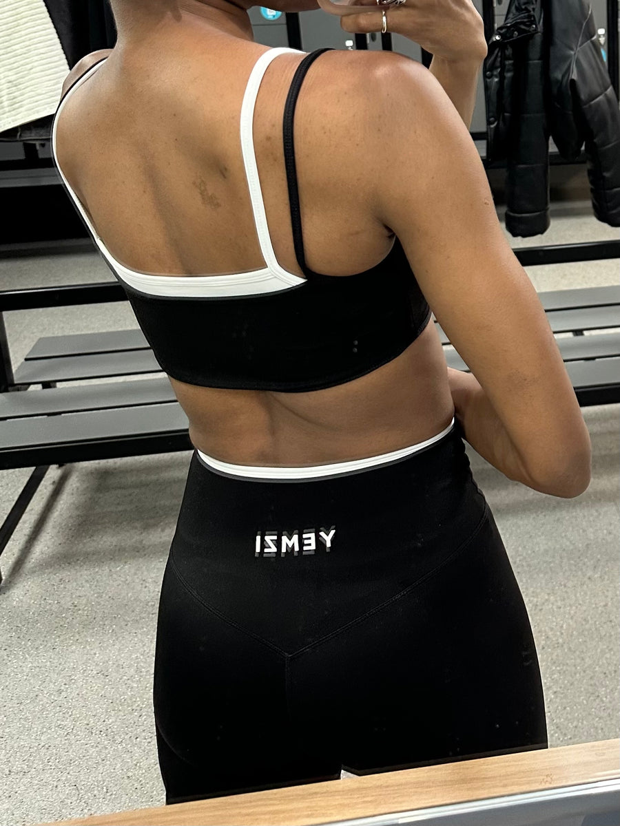 Person wearing a black sports bra and leggings with 'ISMAY' branding.