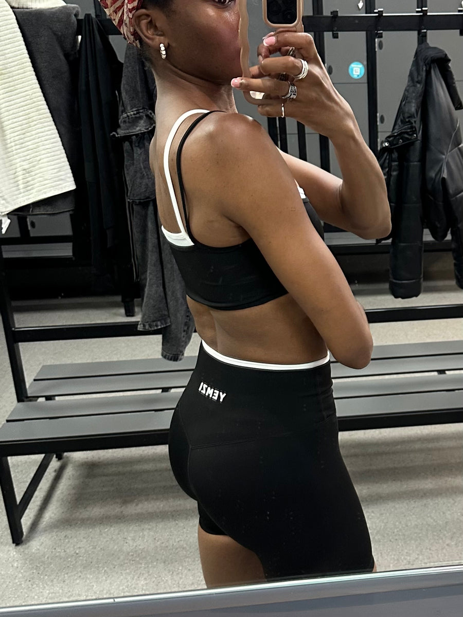 Person wearing a black sports bra and shorts in a gym setting