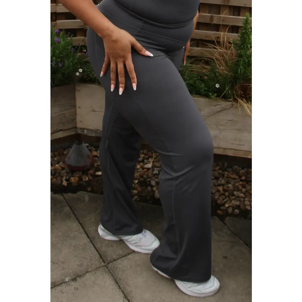 Woman in a gray outfit standing on a rooftop with cityscape in the background
