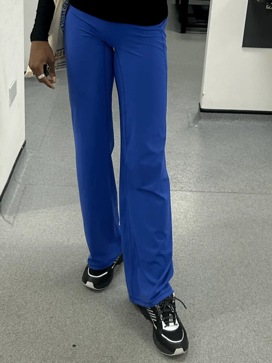Person wearing blue pants standing on a gray floor.