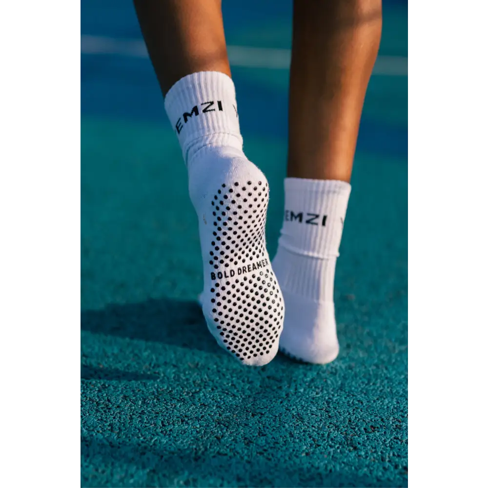 White bold dreamer grip socks with black text on a tennis court