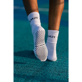 White bold dreamer grip socks with black text on a tennis court