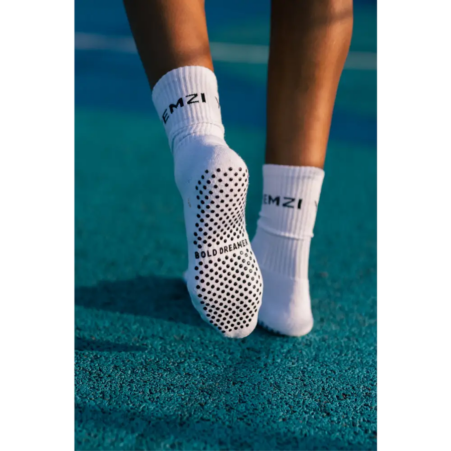 White bold dreamer grip socks with black text on a tennis court