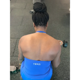Lady in a blue 'YEMZI' tank top lifting a dumbbell outdoors.
