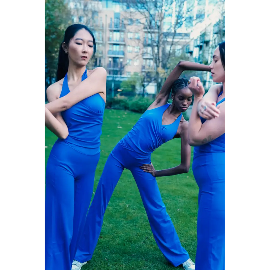 Three women in blue athletic wear posing outdoors with a cityscape background