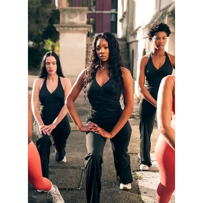 Group of women in athletic wear posing outdoors on a street.