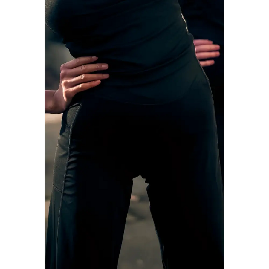 Person wearing a dark green dress with hands on hips against a blurred background