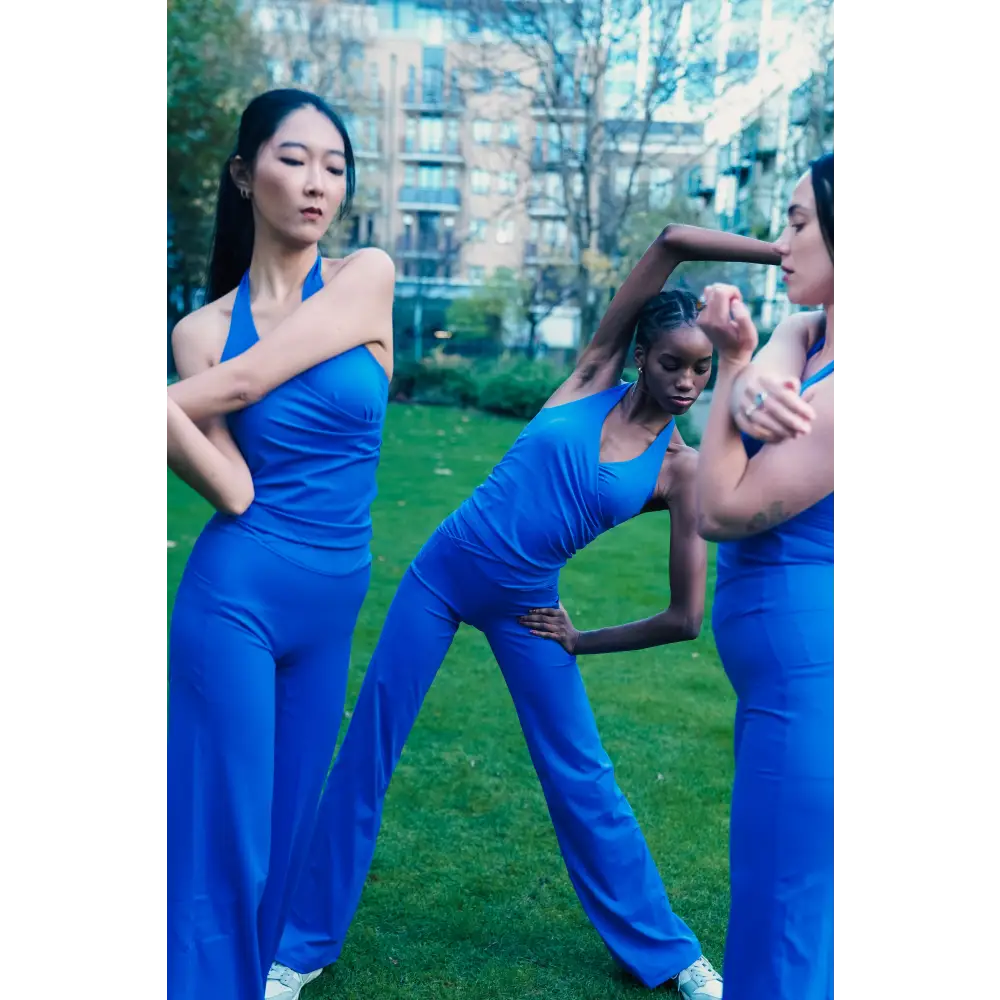 Three women in blue athletic wear posing outdoors with a cityscape background