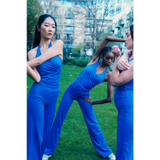 Three women in blue athletic wear posing outdoors with a cityscape background