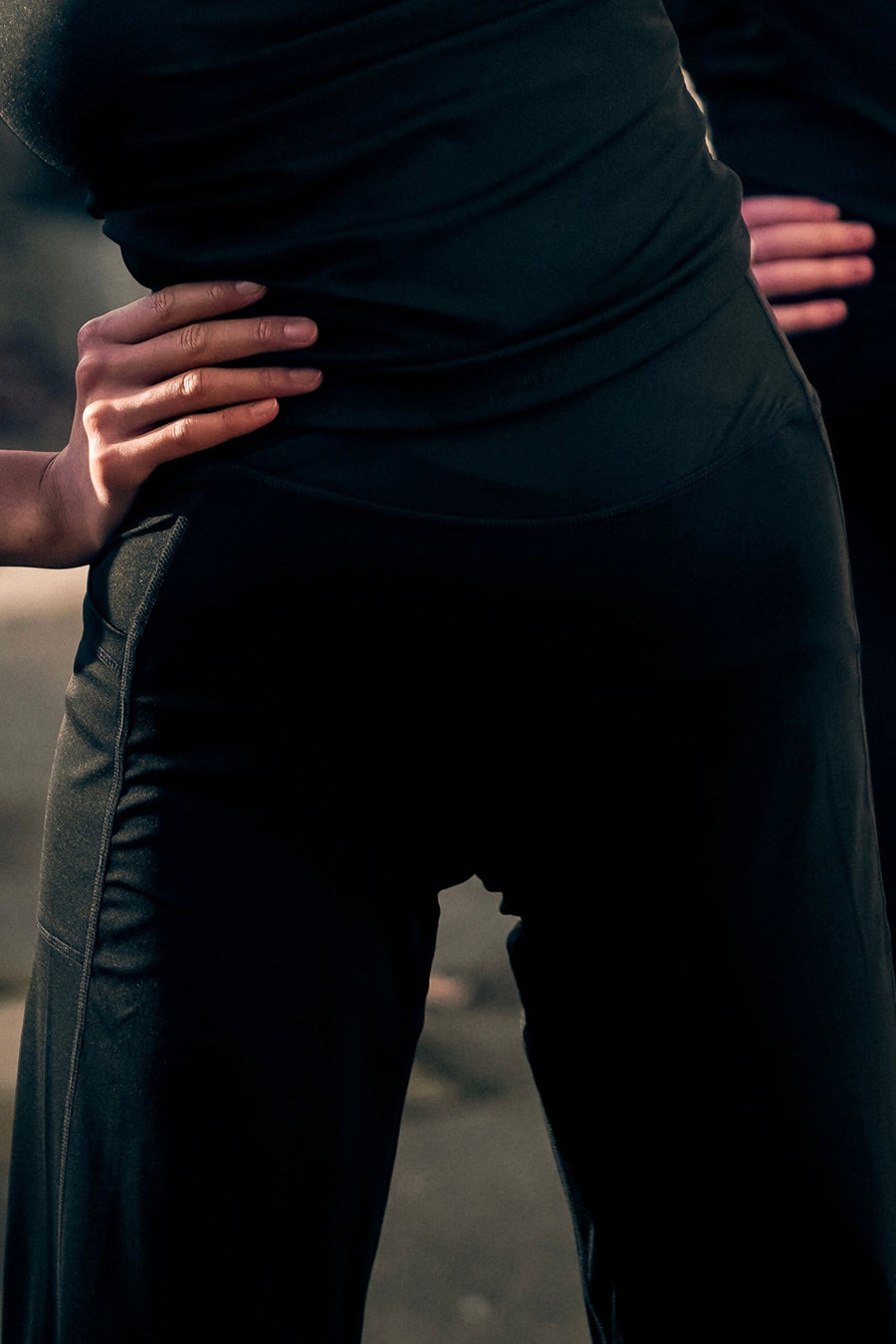 Person wearing a dark green dress with hands on hips against a blurred background