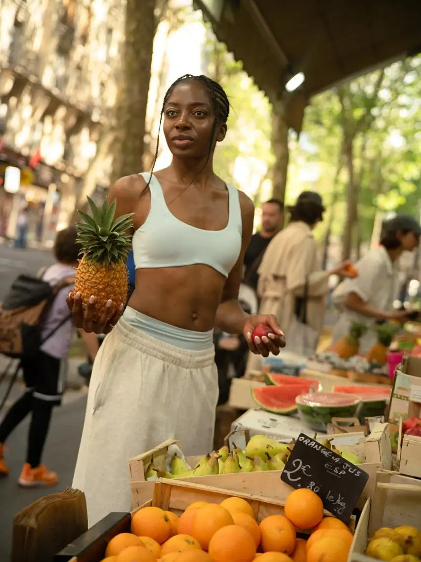A woman holds a ripe, golden-yellow pineapple with its green crown intact.