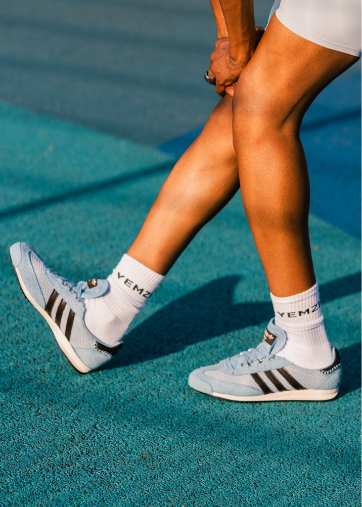 black model wearing light blue grace wales bonner Adidas sneakers with white socks on a tennis court.